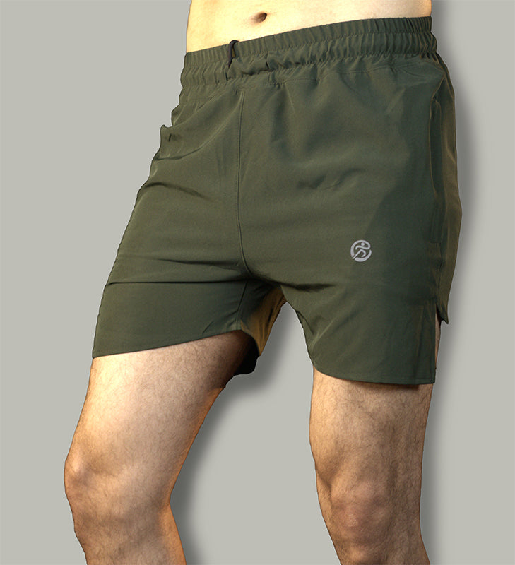 Green shorts for men made of lightweight, stretchy fabric with zip pockets and an adjustable drawstring waist, shown in a lifestyle shot of a man hiking on a trail. The shorts have a regular above-the-knee fit and a sporty green color.